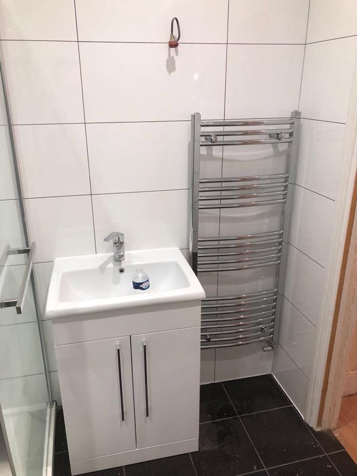 Fitted bathroom with basin unit, chrome towel radiator and full-height tiling