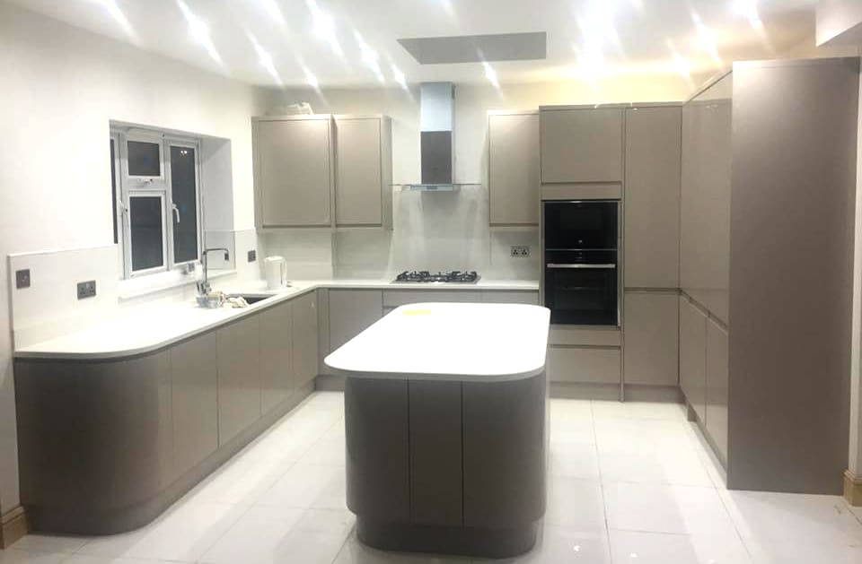 Large grey handleless kitchen with island and recessed lighting