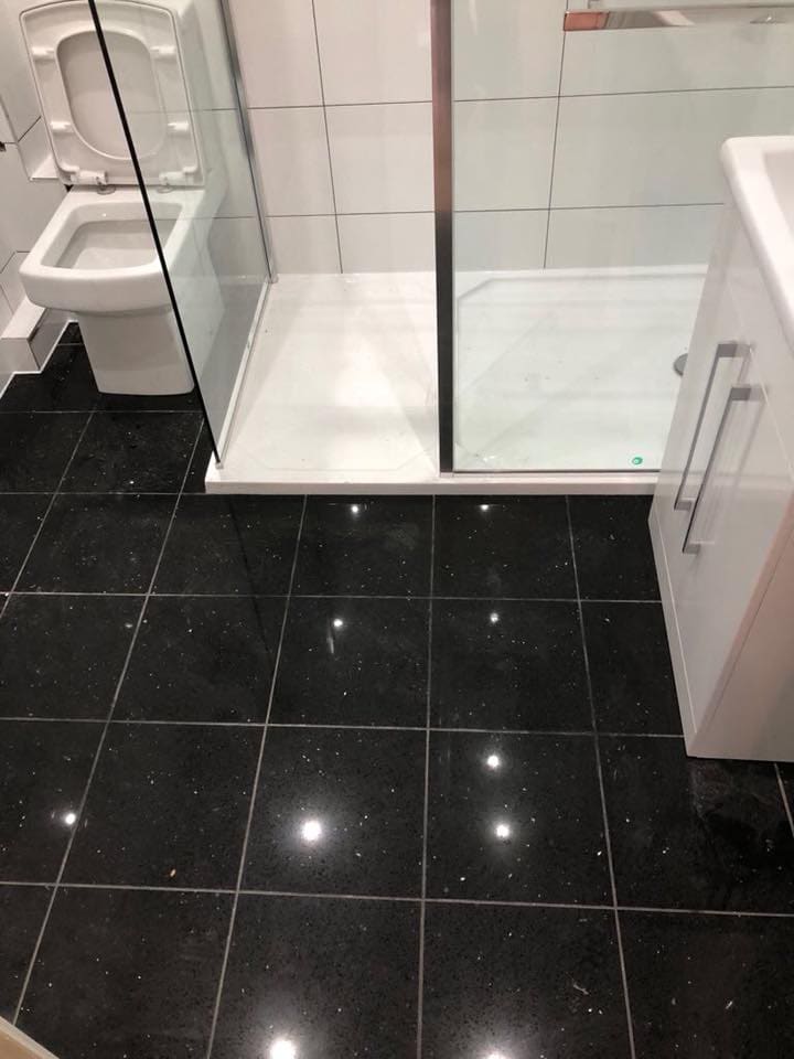 Bathroom with polished black floor tiles and white furniture