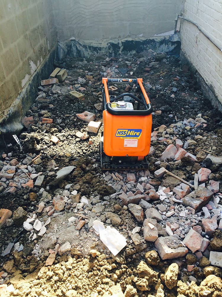 Plate compactor on rubble sub-base during groundworks