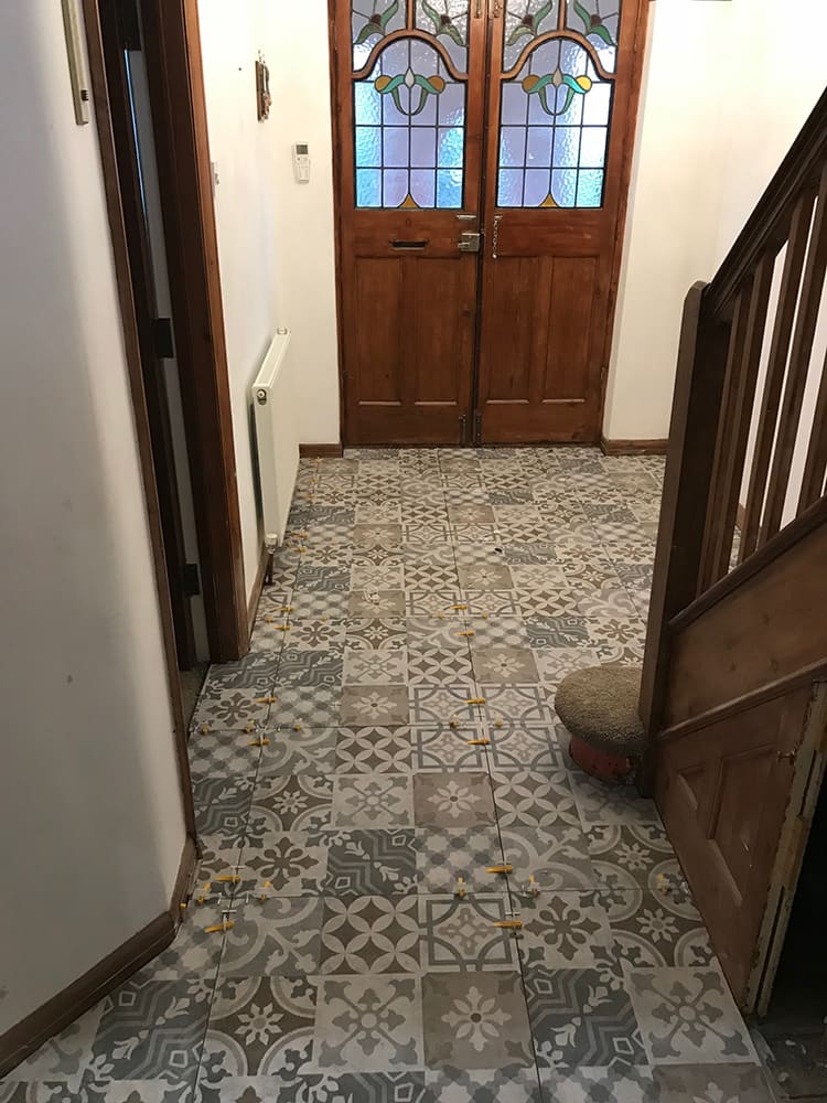 Original patterned floor tiles in a hallway during refurbishment