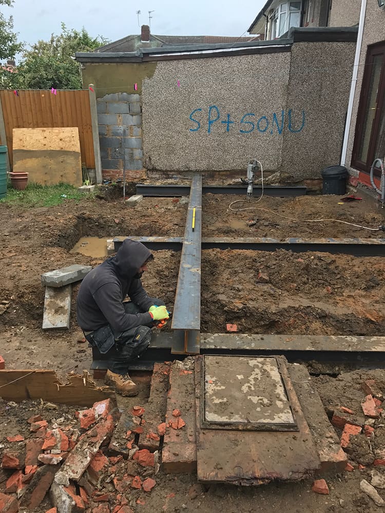 Steel beam being prepared over footings during structural work
