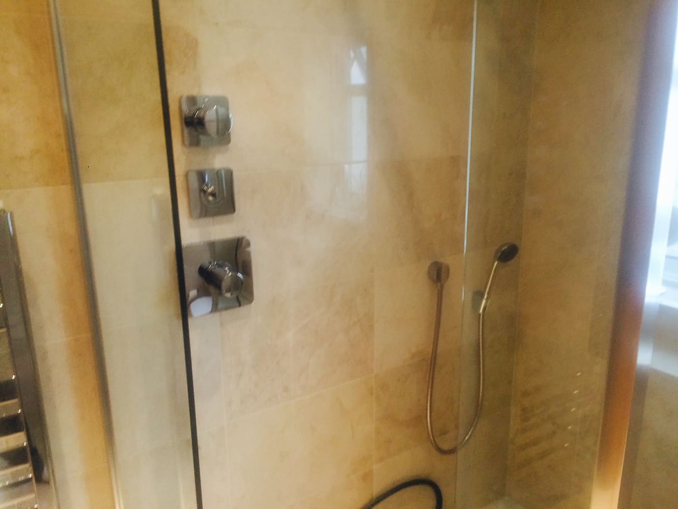 Travertine-tiled shower room with glass enclosure