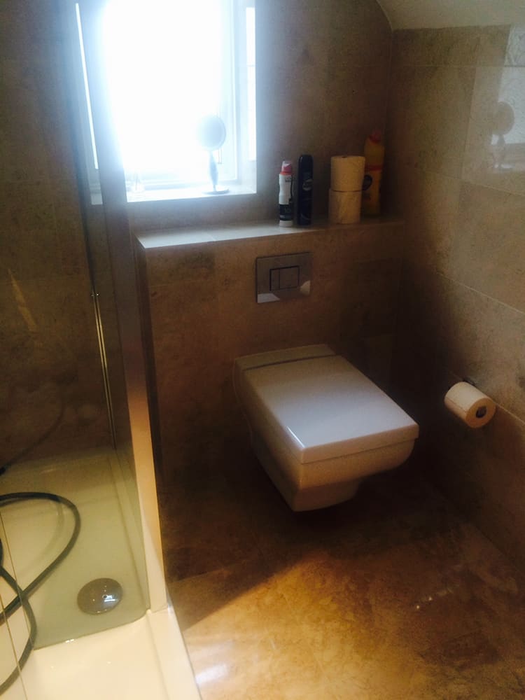 Wall-hung WC in the travertine-tiled bathroom