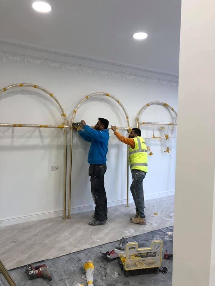 Team fixing gold arch display fittings to the wall