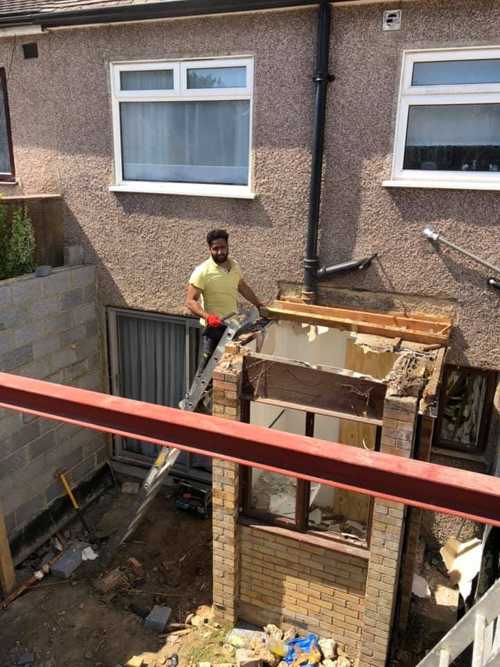 Operative positioning a red-oxide steel beam over the new opening