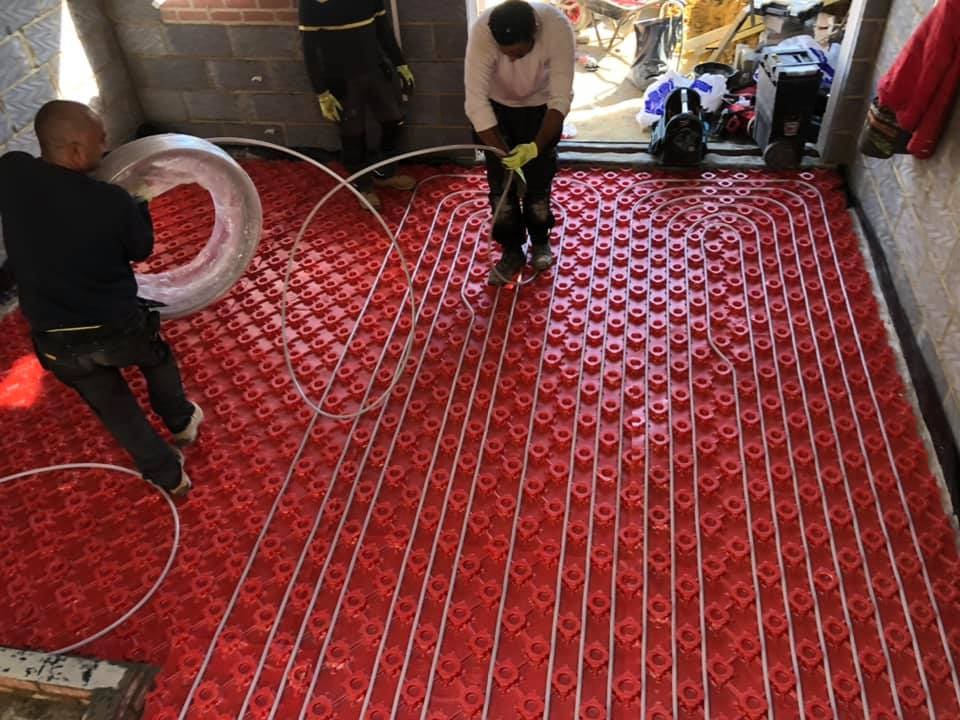 Operatives laying and clipping underfloor heating loops