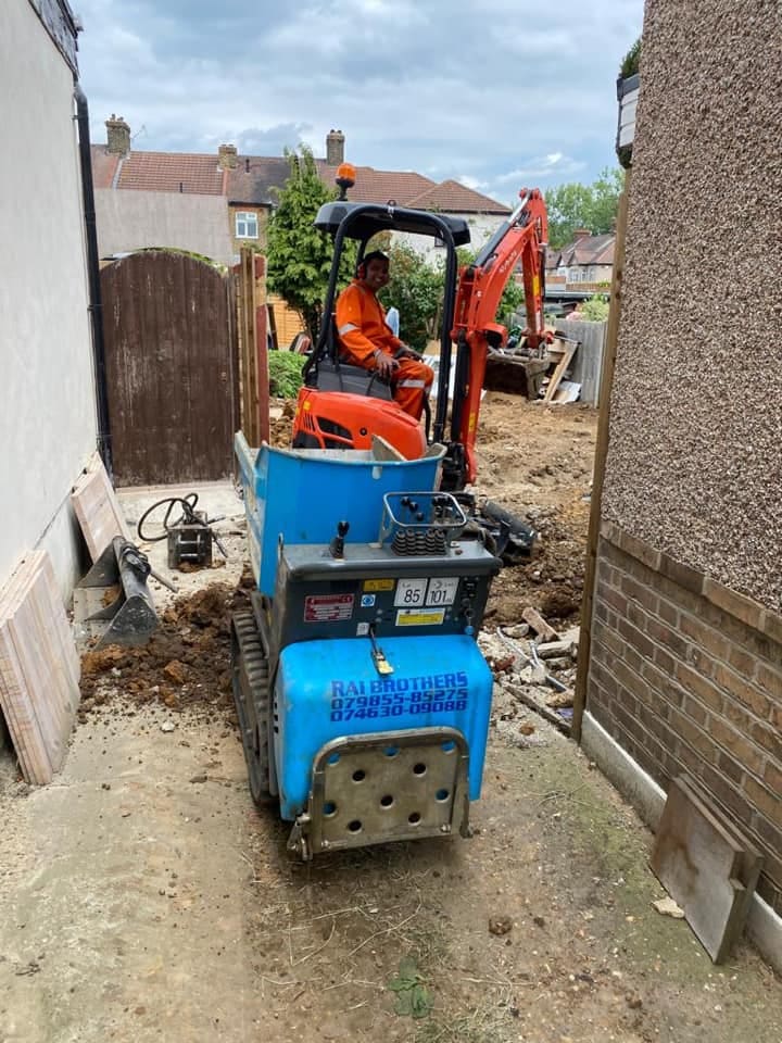 Mini digger and breaker excavating footings at the rear of the house