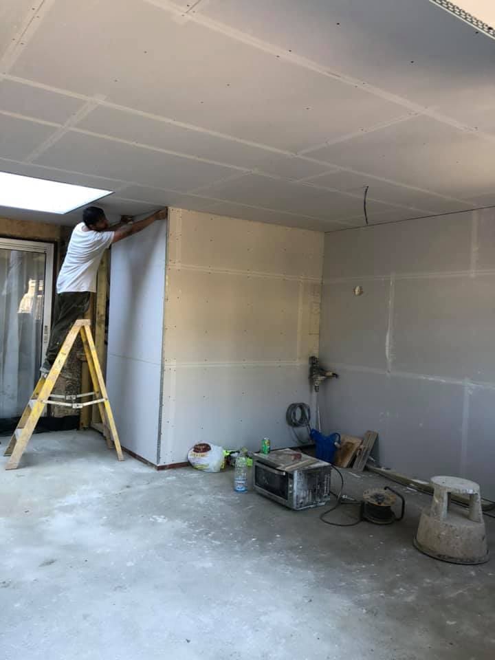 Plasterer working on fresh boarded walls inside the extension