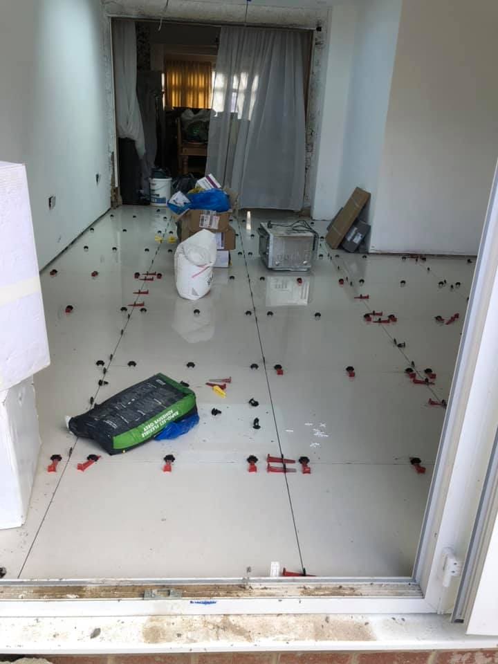 Polished porcelain floor tiles with levelling clips mid-installation