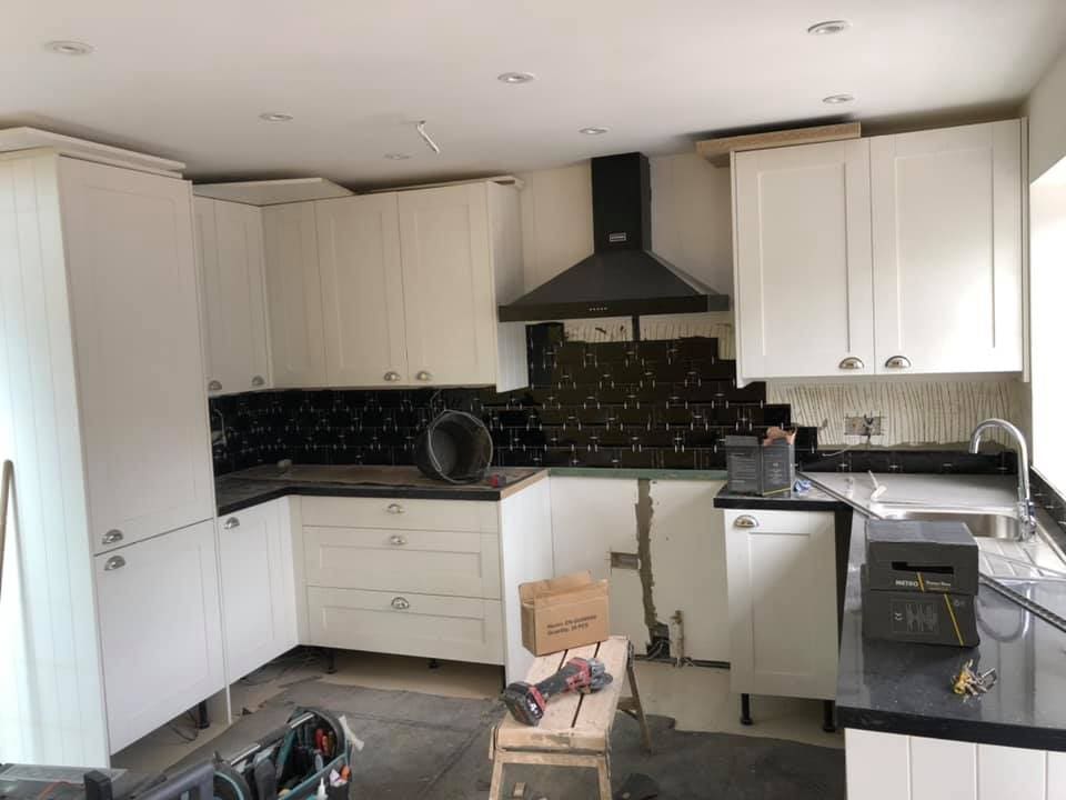White shaker kitchen units being fitted with black metro splashback