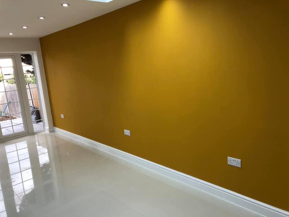 Open-plan room with deep ochre feature wall and polished porcelain floor