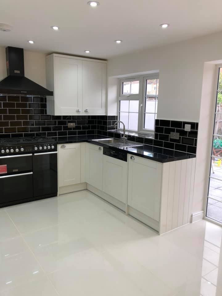 Completed kitchen run with black worktops and white cabinets
