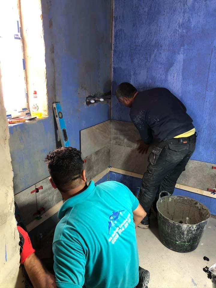 Blue tanking membrane behind wall tiling in progress