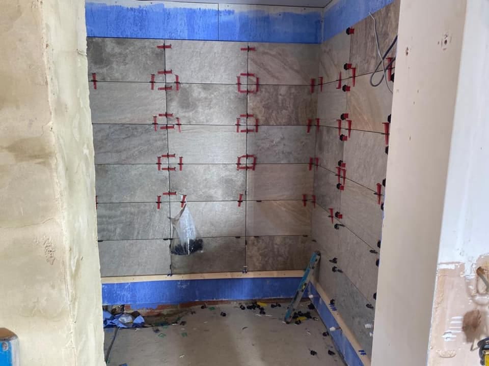 Stone-effect wall tiles being set out with levelling clips