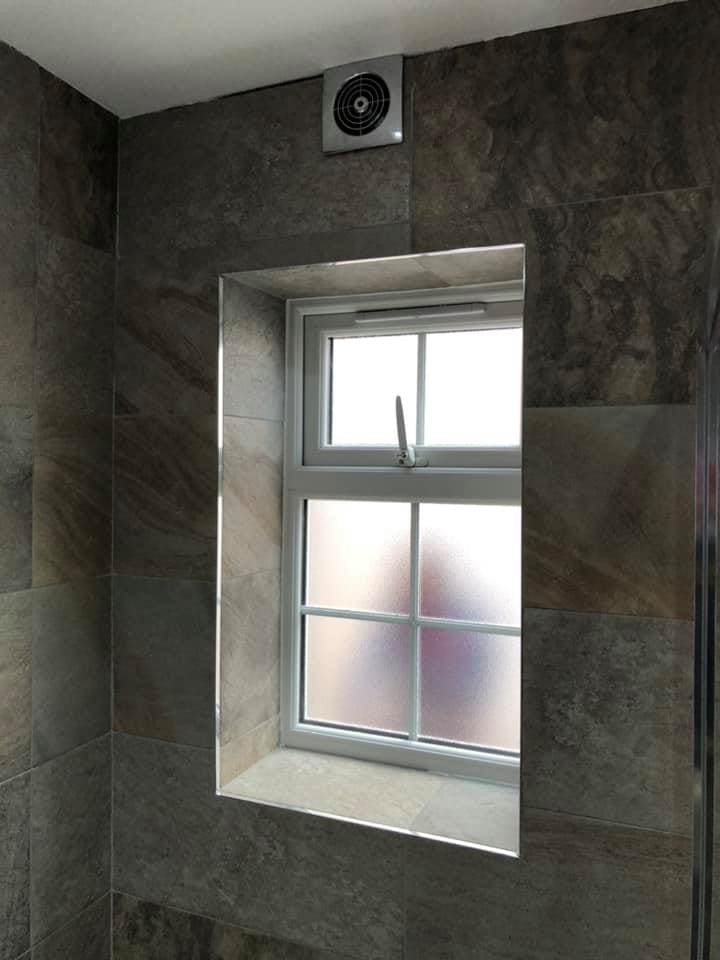 Stone-tiled bathroom window wall with towel radiator