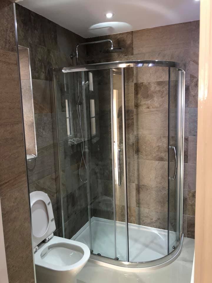 Completed shower enclosure against stone-effect tiles