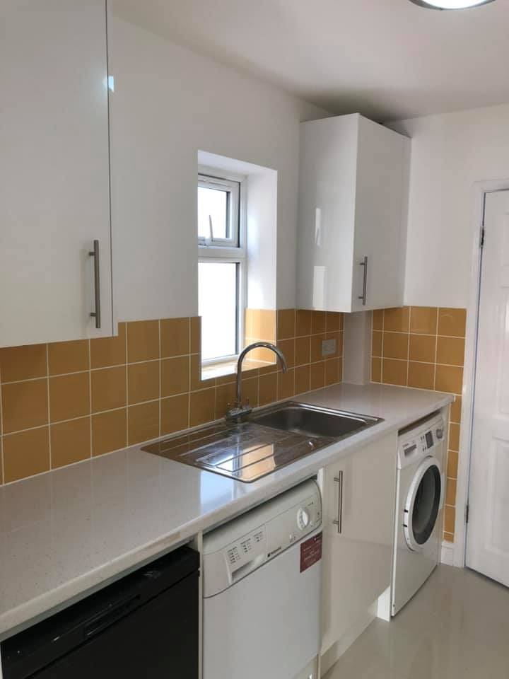 White kitchen units fitted against ochre wall tiles