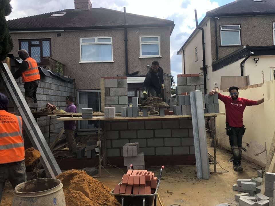Bricklayers raising blockwork walls with materials staged on a board